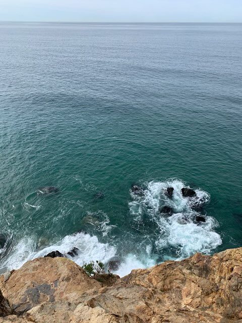 Ocean with rocks and waves crashing against cliff.