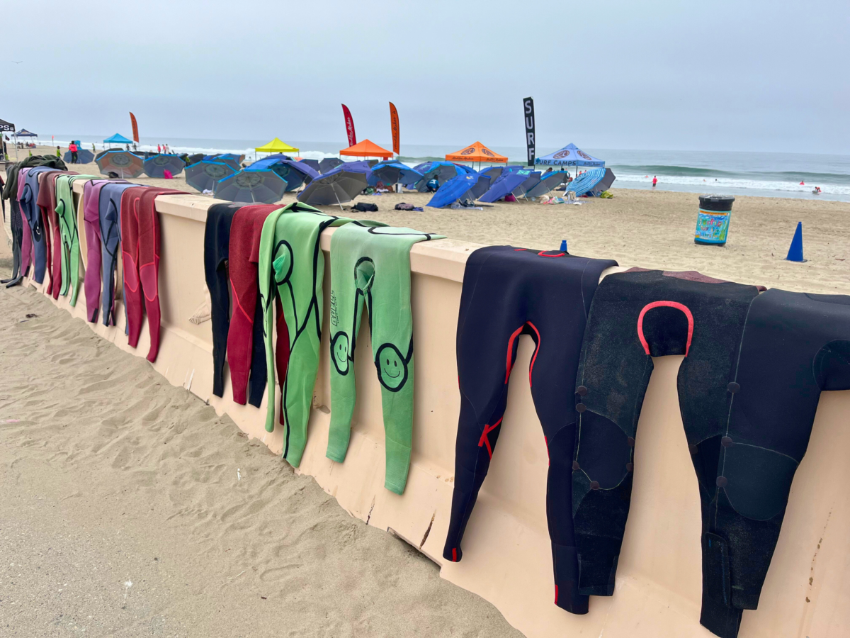 Malibu Makos wet suits drying on a beach wall.