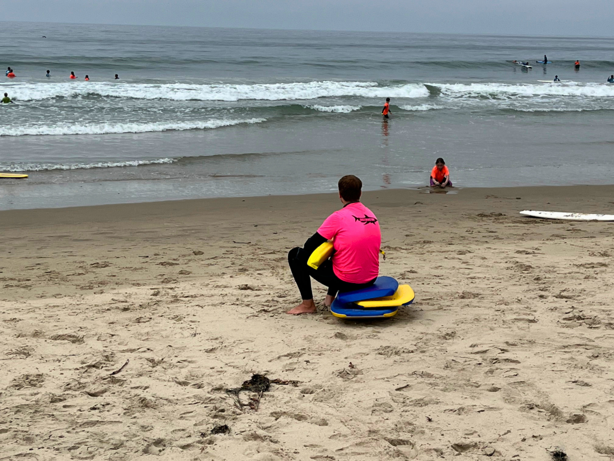 Malibu Makos lifeguard sitting on surf boards looking out at the ocean.